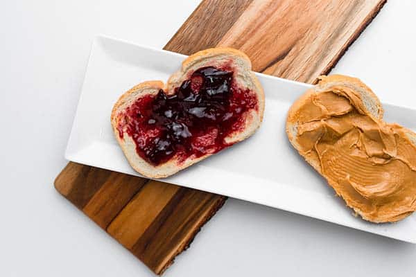 Two slices of bread with jelly spread on one slice peanut butter on the other