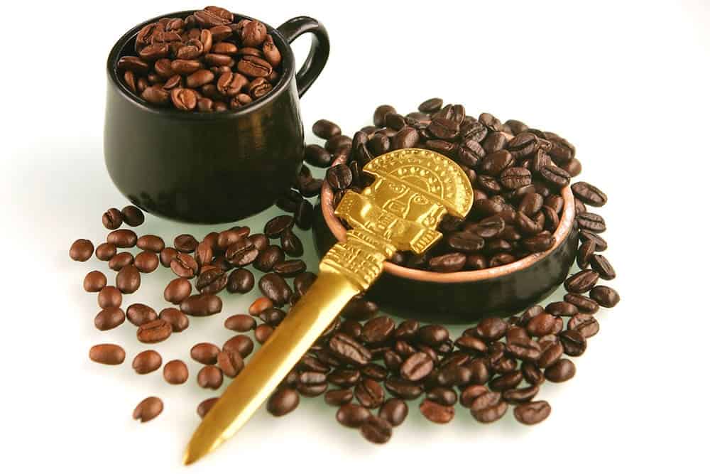Two types of coffee beans in a cup and a bowl and a knife on top