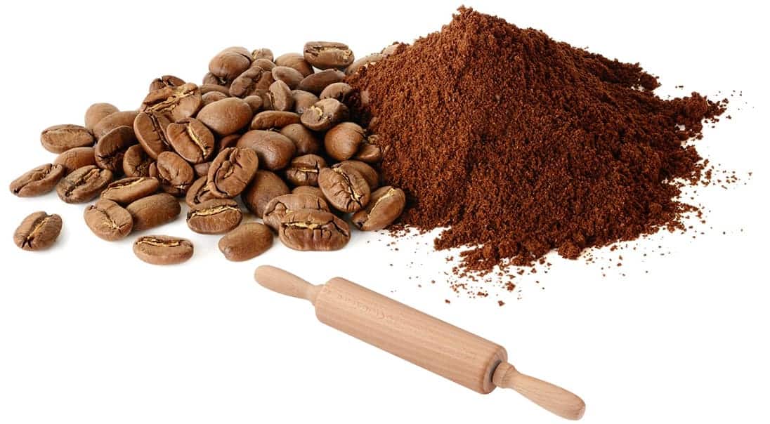 Pile of coffee beans and ground coffee and a rolling pin