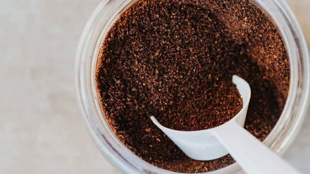 White tablespoon scooping ground coffee