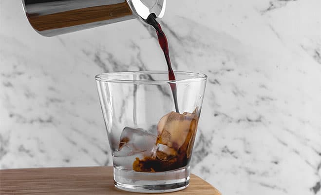 Pouring Cold brew coffee in a glass with ice cubes