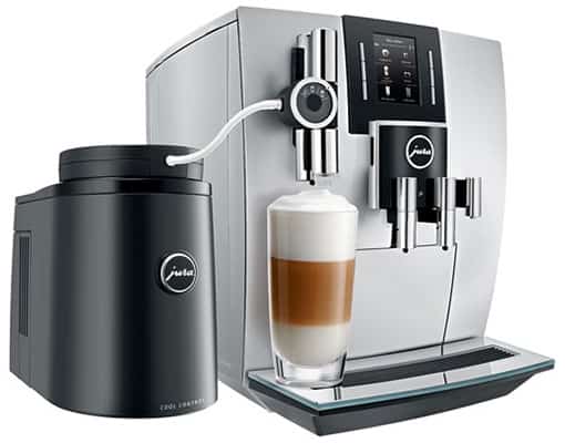 The Jura J6 Automatic Coffee Machine with its milk carafe and a glass filled with specialty drink under its milk spout