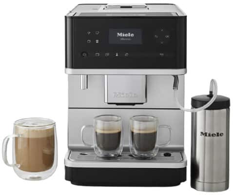 Miele CM6350 Superautomatic with two full espresso glasses on the drip tray and a cup of cappuccino beside the machine