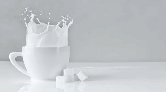 sugar cubes beside a cup of milk