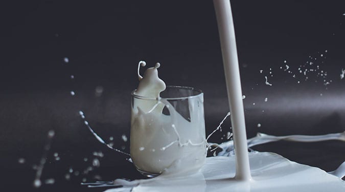 a splash of whole milk in a small glass and on the table