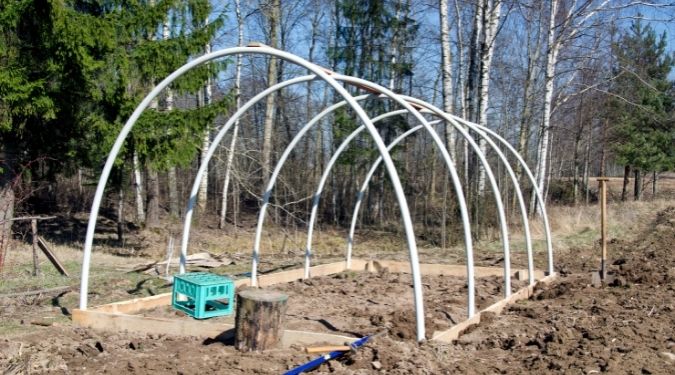 installing a greenhouse frame and digging the soil surrounding it to groom the soil surface