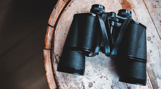 black binoculars with strap on a wooden table