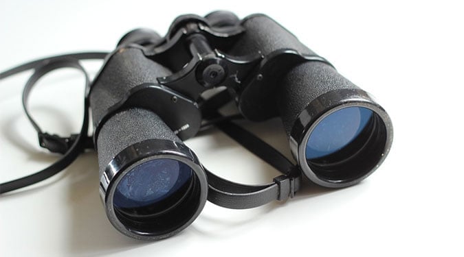Black binoculars with strap on a white table
