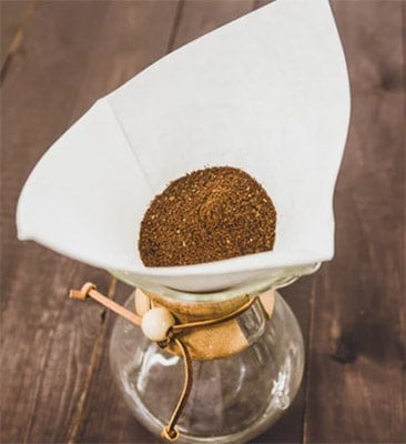 ground coffee on a filter over a glass carafe