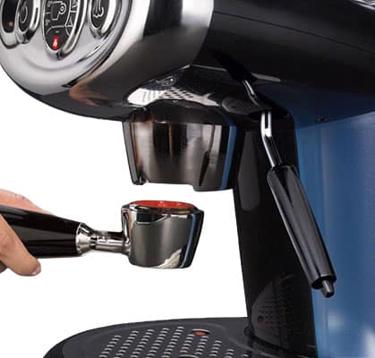 Person holding a portafilter to insert into the Illy X7.1 iperEspresso machine black variant
