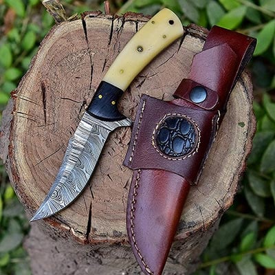 BG Knives Damascus Steel Knife and genuine leather sheath over a piece of chopped wood log outdoors